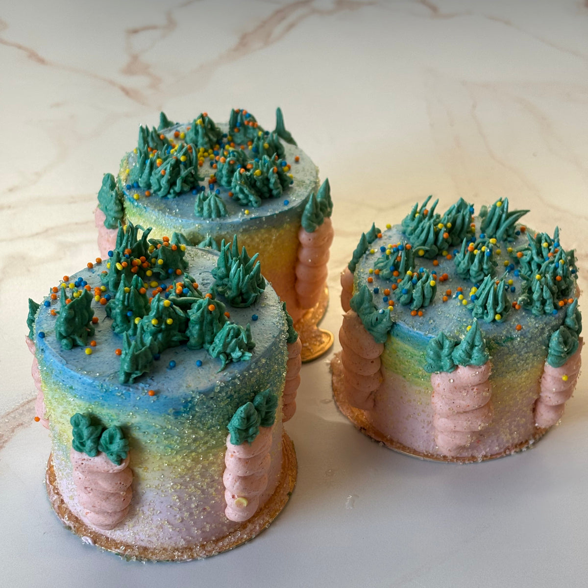 Pair of carrots and grass with pink, yellow and blue ombre design on a marble surface